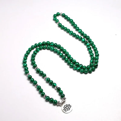 Mala 108 perles Malachite et symbole du Lotus (boule 6 mm) déroulé sur un sol blanc Kaosix