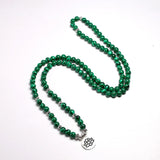 Mala 108 perles Malachite et symbole du Lotus (boule 6 mm) déroulé sur un sol blanc Kaosix