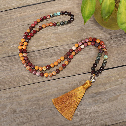 Mala 108 perles Obsidienne Acajou, Jaspe Mokaite, Turquoise Africaine deroulé et posé sur un plancher en bois Kaosix