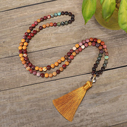 Mala 108 perles Obsidienne Acajou, Jaspe Mokaite, Turquoise Africaine deroulé et posé sur un plancher en bois Kaosix