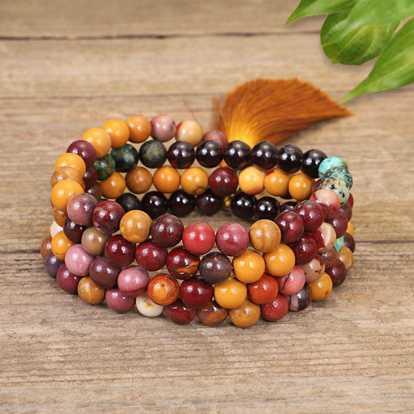 Mala 108 perles Obsidienne Acajou, Jaspe Mokaite, Turquoise Africaine enroulé vue en gros plan et posé sur un plancher en bois Kaosix
