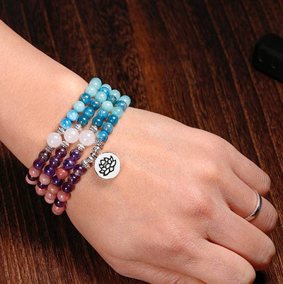 Mala 108 perles Rhodochrosite Apatite Améthyste Pierre de Soleil au poignet d'une femme et en gros plan Kaosix