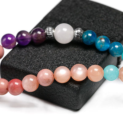 Mala 108 perles Rhodochrosite Apatite Améthyste Pierre de Soleil en gros plan posé sur une pierre noire Kaosix
