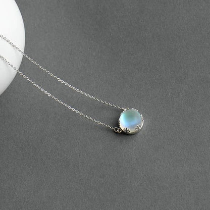 Pendentif Aurore Boréale perle de cristal bleu clair couronne argentée sur tapis gris Kaosix