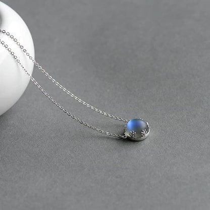 Pendentif Aurore Boréale perle de cristal bleu fonce couronne argentée sur tapis gris Kaosix