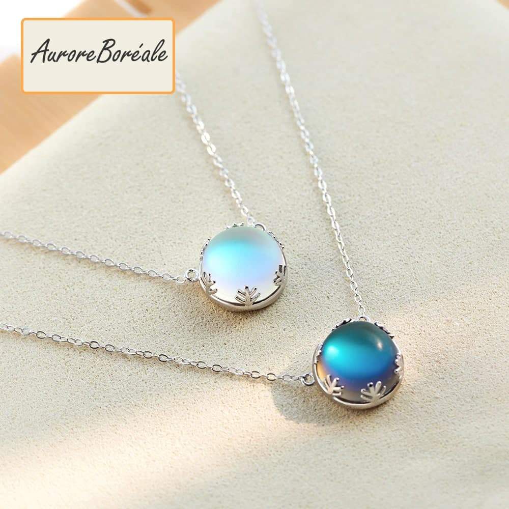 Pendentif Aurore Boreale perle de cristal bleu foncé et bleu clair couronne argentée sur tapis beige Kaosix