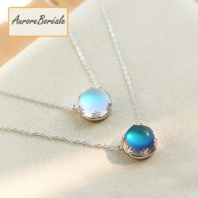 Pendentif Aurore Boreale perle de cristal bleu foncé et bleu clair couronne argentée sur tapis beige Kaosix