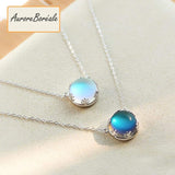 Pendentif Aurore Boreale perle de cristal bleu foncé et bleu clair couronne argentée sur tapis beige Kaosix