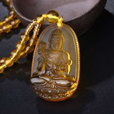 Pendentif Bouddha Bodhisattva en Citrine posé sur un bol et sur une table noire Kaosix