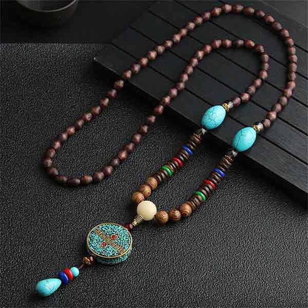 Pendentif et collier ethnique népalais Soleil en bois sur une table grise foncée Kaosix