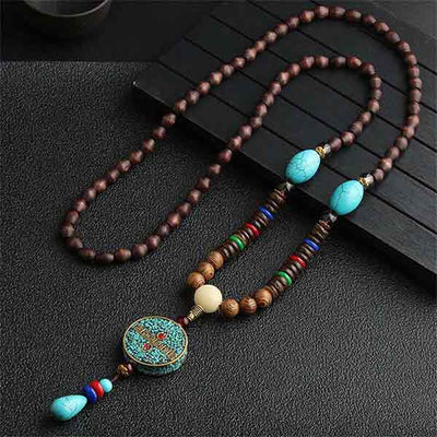 Pendentif et collier ethnique népalais Soleil en bois sur une table grise foncée Kaosix