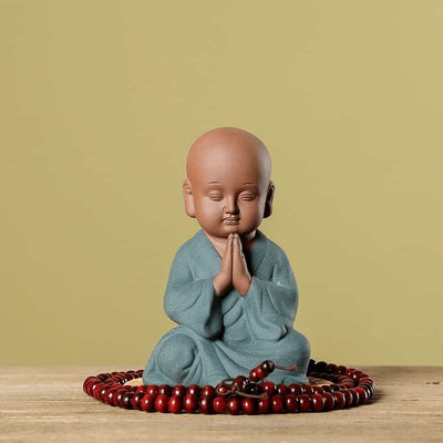 Petite statue moine bouddhiste salutation sur fond vert Kaosix