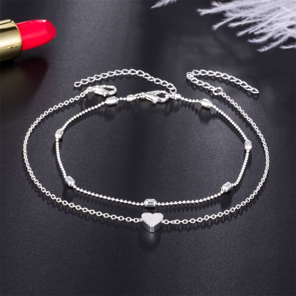 Set de deux bracelets de cheville avec amulette cœur couleur argenté sur sol noir Kaosix
