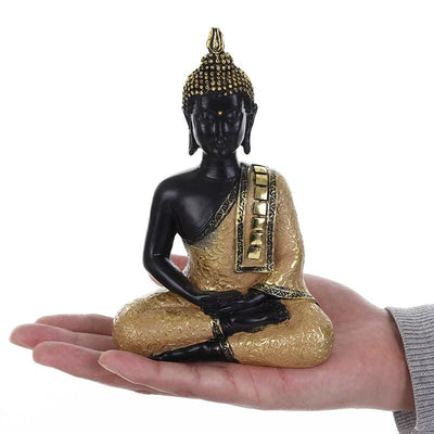 Statue Bouddha assis Dhyana mudra couleur dorée posé sur une main d'homme et sur un fond blanc kaosix