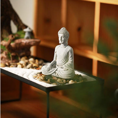 Statue Bouddha assis appel à la terre posé sur un mini jardin japonais avec étagère en bois en fond Kaosix