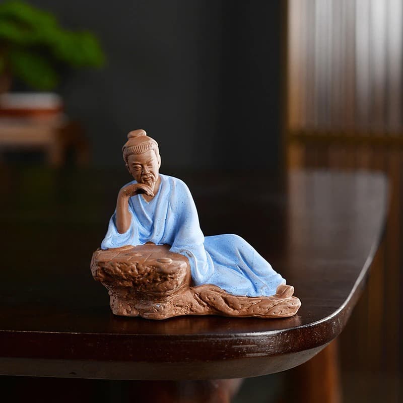 Statue chinoise personnage historique Lu Yu Le maitre du thé posée sur une table en bois laqué sombre avec un fond flou Kaosix