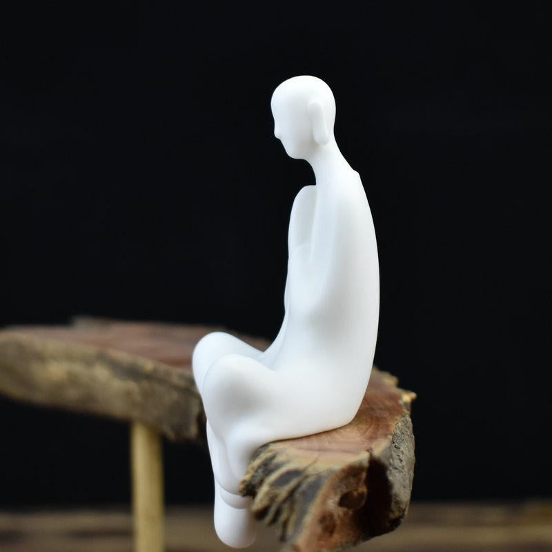 Statue moine bouddhiste zen céramique blanche pose Abhaya mudra assis sur banc en bois avec fond noir Kaosix