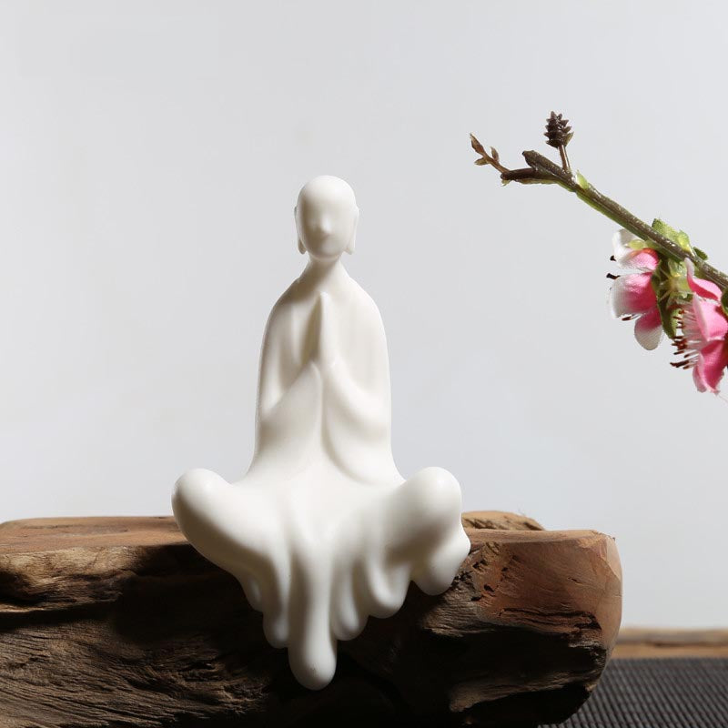 Statue moine bouddhiste zen céramique blanche pose anjali mudra assis sur banc en bois et fond gris Kaosix