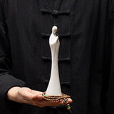 Statue moine debout blanc Namaste sur une main d'homme qui porte une chemise noire Kaosix