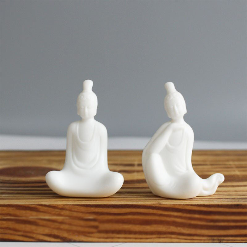 Statuette bouddha assis 4 posturesentre repos et éveil assis sur une planche en bois avec un fond gris Kaosix