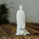 Statuette moine bouddhiste avec un balai de dos sur une table en bois Kaosix