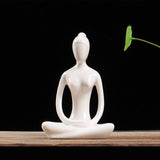Statuette yoga femme posture du lotus mains jointes posee sur table fond noir Kaosix