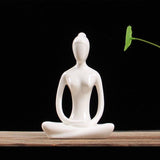Statuette yoga femme posture du lotus mains jointes posee sur table fond noir Kaosix