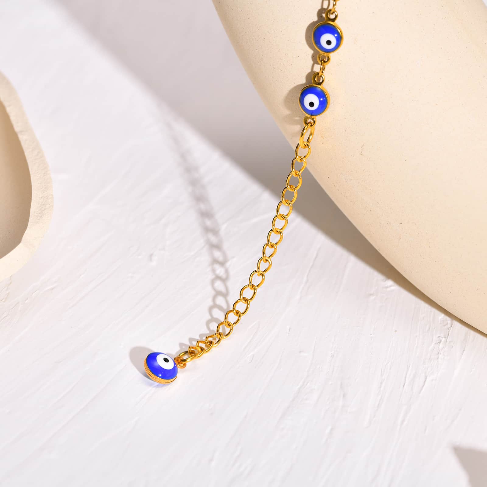 Vue en gros plan du Bracelet de cheville en perles de nazar boncuk bleu avec amulette khamsa posé sur une assiette beige Kaosix