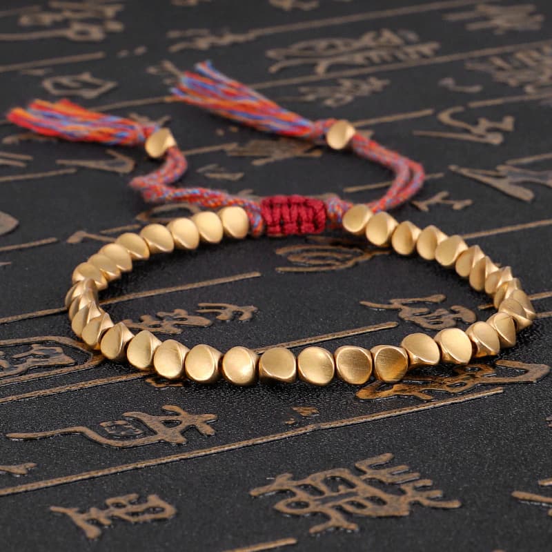 bracelet tibétain en perles de cuivre sur tapis noir avec caractères chinois dorés Kaosix