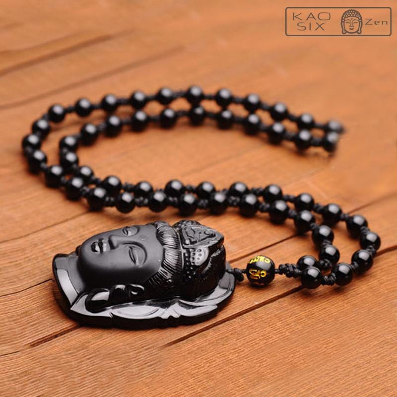 Pendentif tête de Bouddha obsidienne noire posé sur une table en bois kaosix