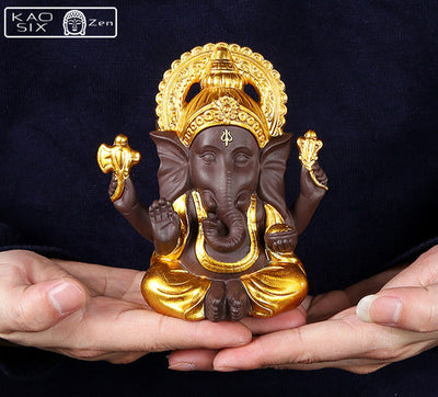 Statue de Ganesh doré posé sur mains d'homme