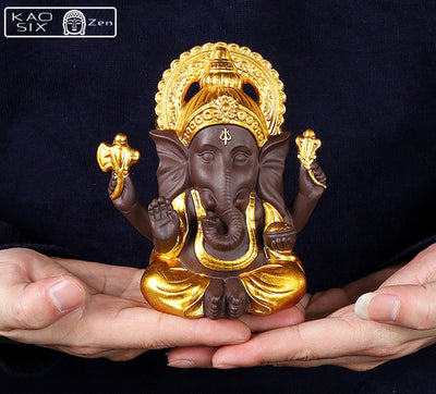 Statue de Ganesh doré posé sur mains d'homme