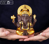 Statue de Ganesh doré posé sur mains d'homme