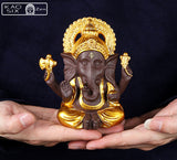 Statue de Ganesh doré posé sur mains d'homme