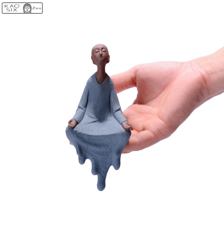Statue moine zen regard en l'air et assis sur une main d'homme kaosix